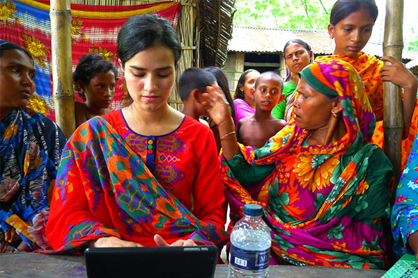 Student submerged in international culture surrounded by women and children in vibrant colors.