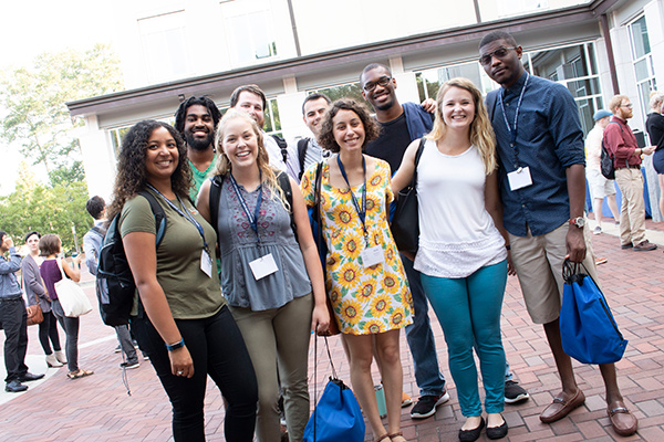 A group of nine diverse male and female students pose and smile during orientation.